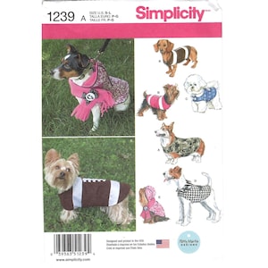 May include: Simplicity sewing pattern 1239 for dog clothing. The envelope features illustrations and photographs of various dogs wearing coats, sweaters, and scarves in different patterns including camouflage, plaid, and a football design.