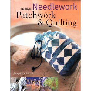 May include: A book cover titled "Needlework Patchwork & Quilting" by Jacqueline Farrell. A blue and white checkered drawstring bag is in the foreground. The background is a light brown surface with a wooden carving.