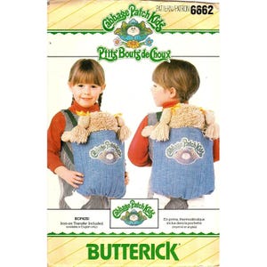 May include: A vintage Butterick sewing pattern featuring Cabbage Patch Kids. The pattern includes instructions for a child's backpack with a doll head design. The packaging is primarily white, green, and yellow, with the Cabbage Patch Kids logo prominently displayed.