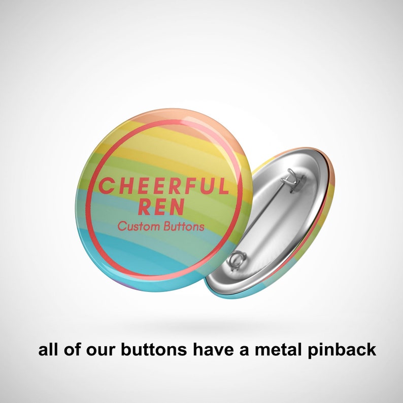 Puede incluir: Dos chapas redondas con un fondo de rayas arco&iacute;ris. La chapa frontal muestra el texto rojo CHEERFUL REN y Custom Buttons dentro de un c&iacute;rculo rojo. La segunda chapa muestra el mecanismo de cierre de metal de color plateado.