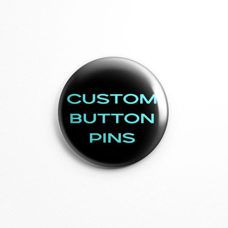 May include: A black button pin with the text "CUSTOM BUTTON PINS" in light blue.