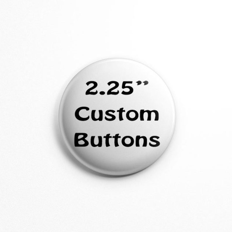 Puede incluir: Un bot&oacute;n circular blanco con texto negro impreso en el frente. El texto dice 2.25" Custom Buttons, indicando el di&aacute;metro del art&iacute;culo. El bot&oacute;n tiene una superficie lisa y redondeada con un dise&ntilde;o limpio y sencillo para usar como insignia.