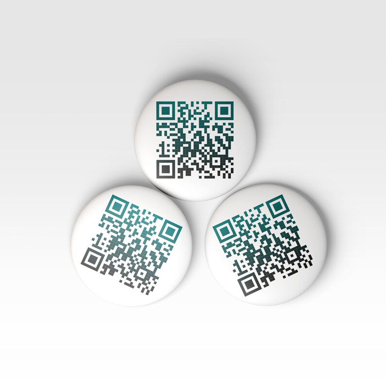 K&ouml;nnte beinhalten: Drei wei&szlig;e runde Kn&ouml;pfe mit schwarzen und t&uuml;rkisfarbenen QR-Codes darauf gedruckt.