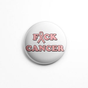 Puede incluir: Botón blanco con una cinta rosa y el texto "FCK CANCER" en letras rosas.