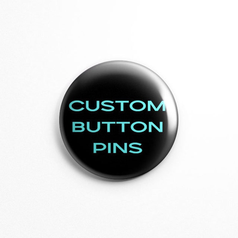 May include: A black button pin with the text "CUSTOM BUTTON PINS" in light blue.
