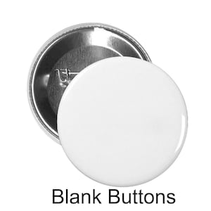 May include: Two blank, white, round buttons with a shiny, reflective surface. One button is face up, and the other is face down, revealing a silver pin back. The text "Blank Buttons" is printed in black below the buttons.