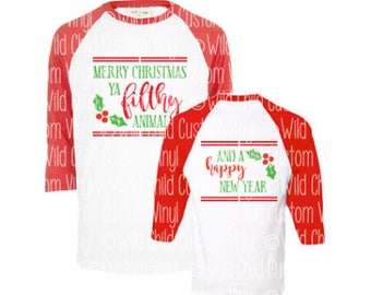May include: Two red and white baseball style shirts with a Christmas themed design. The larger shirt says "Merry Christmas ya filthy animal" with holly and berries. The smaller shirt says "And a happy new year" with holly and berries.