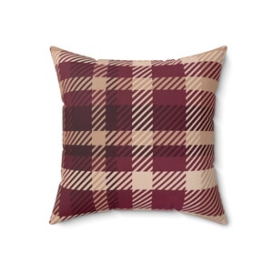 May include: A red and beige plaid cushion with a square shape.
