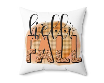 Puede incluir: Cojín blanco con el texto "hello fall" en letra cursiva negra. El texto está sobre un fondo de acuarela con un patrón de cuadros y estampado de leopardo en naranja y marrón.