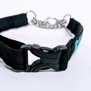 Puede incluir: Collar de perro de nylon negro con una hebilla de pl&aacute;stico negro y una cadena plateada. El collar tiene un dise&ntilde;o bordado azul.
