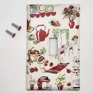 May include: A white light switch cover with a vintage kitchen print featuring red, green, and yellow illustrations of kitchen appliances, fruits, and flowers.