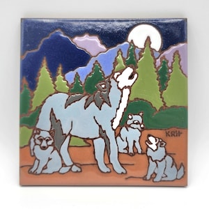 May include: Square ceramic tile featuring a wolf howling at the moon with three pups. The artwork is set against a backdrop of green trees, purple mountains, and a dark blue sky. The tile has a brown border.