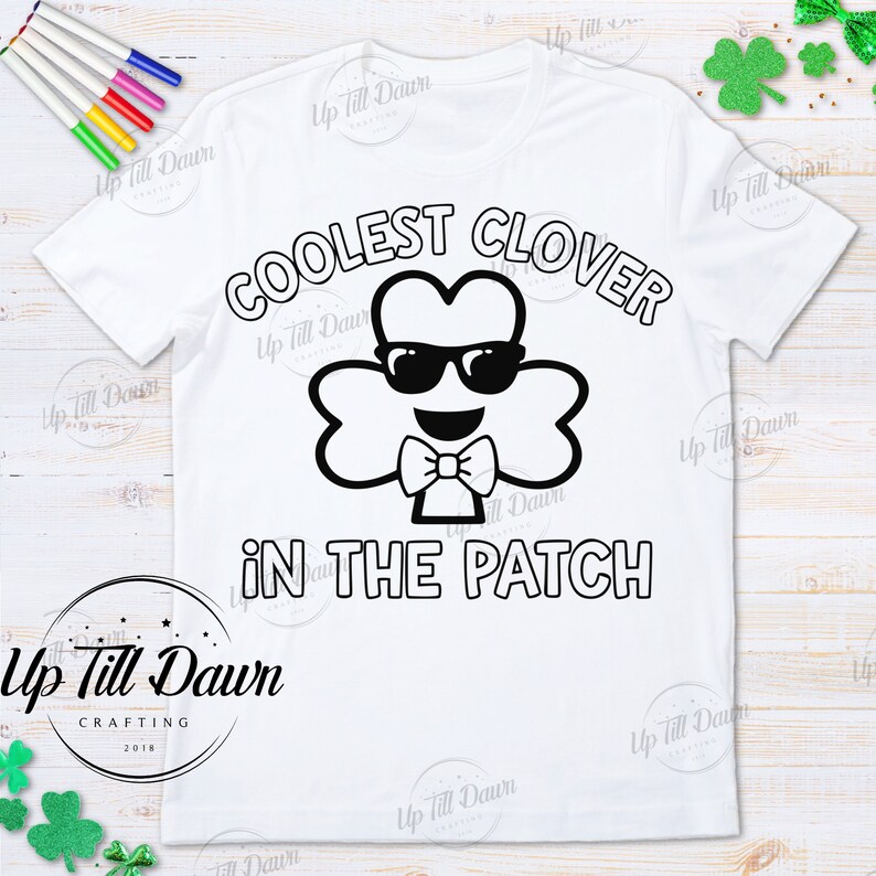 Puede incluir: Una camiseta blanca con un dise&ntilde;o en blanco y negro de un tr&eacute;bol con gafas de sol y una pajarita. El texto "COOLEST CLOVER IN THE PATCH" est&aacute; impreso en la camiseta.