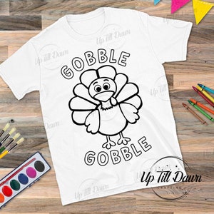 May include: A white t-shirt with a black outline of a turkey and the words "Gobble Gobble".