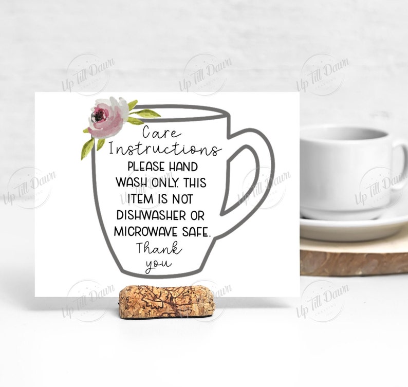 K&ouml;nnte beinhalten: Eine wei&szlig;e Karte mit einer grauen Umrandung einer Kaffeetasse und einem rosafarbenen Blumendesign. Die Karte lautet "Pflegehinweise Bitte nur von Hand waschen. Dieser Artikel ist nicht sp&uuml;lmaschinen- oder mikrowellengeeignet. Danke".