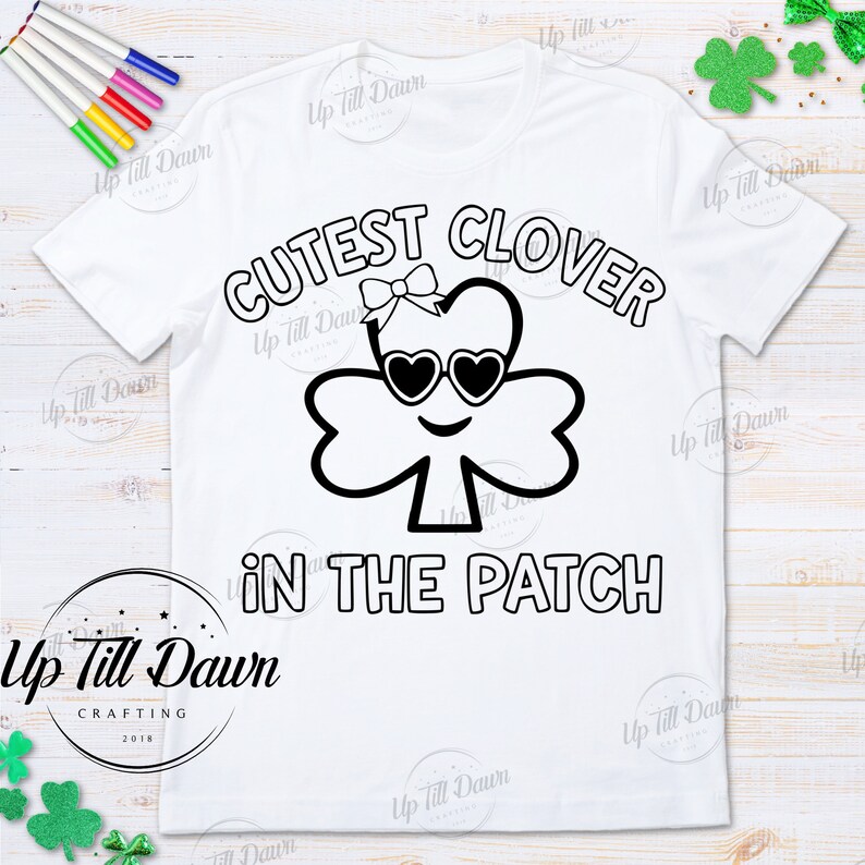 May include: A white t-shirt with a black and white design of a clover with sunglasses and a bow. The text "CUTEST CLOVER IN THE PATCH" is written around the clover.