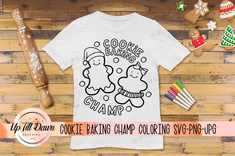 Op de afbeelding: Een wit T-shirt met een zwart-witte illustratie van twee gingerbread-mensen. De tekst "Cookie Baking Champ" staat in een cirkel rond de gingerbread-mensen.
