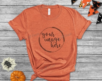 May include: A burnt orange t-shirt with a black circle design that says "your image here" on a wood background with Halloween decorations.