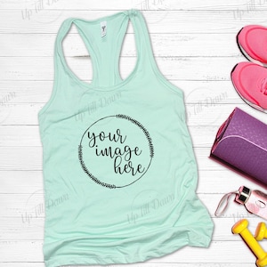 May include: A light blue tank top with a black circle design that says "your image here" on a white wood background. The tank top is laying flat with a yoga mat, water bottle, and weights beside it.