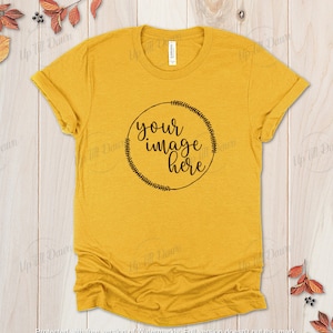 Könnte beinhalten: Ein senfgelbes T-Shirt mit einem schwarzen Kreisdesign, auf dem in kursiver Schrift "your image here" steht. Der Kreis ist von einem Kranz aus kleinen Blättern umgeben.