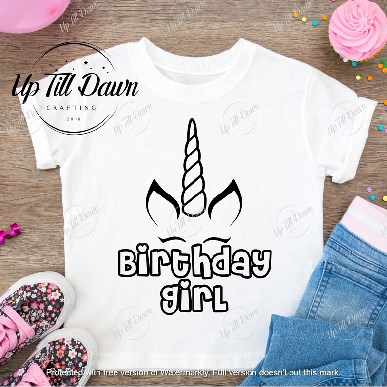 May include: White t-shirt with a black unicorn design and the text "Birthday girl".