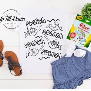 Pode incluir: Uma camiseta branca com um contorno preto de peixes e as palavras "Splish Splash" repetidas. A camiseta est&aacute; sobre uma superf&iacute;cie branca com um par de sand&aacute;lias marrons e um pacote de marcadores Crayola Fabric Fine Line.