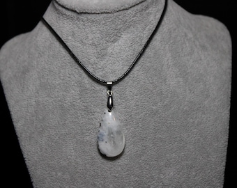 May include: A teardrop-shaped pendant necklace with a white and gray stone. The pendant hangs from a black cord necklace. The necklace is displayed on a gray mannequin bust against a black background.