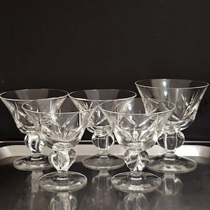 May include: Set of six clear glass stemmed dessert dishes with a cut glass design. The dishes have a round bowl and a short stem with a round base.
