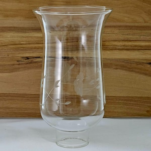 Peut inclure: Un abat-jour en verre transparent avec un dessus évasé et un motif floral gravé. L'abat-jour a une forme cylindrique avec une base et convient aux bougies ou à l'éclairage décoratif.