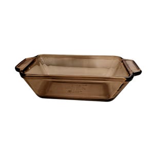 May include: A rectangular baking dish made of translucent brown glass. The dish features integrated handles on both short ends and has a smooth, polished finish. Embossed text is visible on the interior base of the glass bakeware.