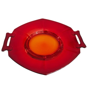 May include: A red, diamond-shaped serving dish with a central orange circle and two side handles. The dish is made of a transparent material. The design is simple and modern, suitable for serving appetizers or small dishes. The dish is approximately 20 cm in diameter.