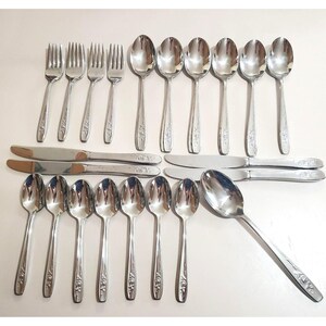 May include: A set of stainless steel cutlery including four forks, eleven spoons of varying sizes, and four dinner knives. Each piece features a polished silver finish and a delicate floral engraving on the handle, providing a consistent look.