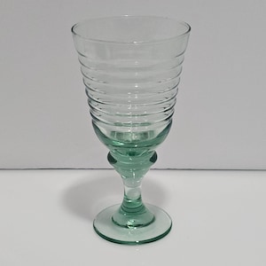 Peut inclure: Un verre transparent avec une tige et une base vertes, présentant un design côtelé sur la partie supérieure. La tige a une forme bulbeuse distinctive. Ce verre est adapté pour servir des boissons et convient à diverses occasions.