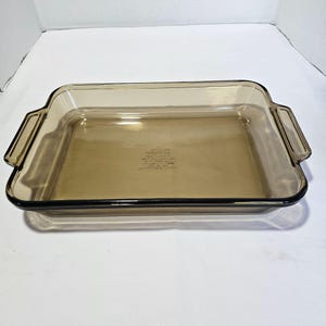 May include: A brown glass baking dish with two handles. The dish is made by Pyrex and is oven safe.