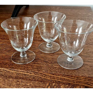 May include: Three clear glass stemmed drinking glasses with a starburst pattern etched into the glass.