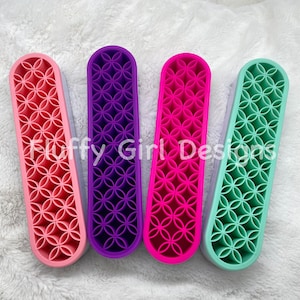 May include: Four colorful silicone hair styling tools in pink, purple, hot pink, and mint green. Each tool has a floral pattern and the text "Fluffy Girl Designs". These tools are designed for hair styling.