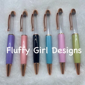 Puede incluir: Seis bolígrafos transparentes con detalles en oro rosa y cuerpos de diferentes colores. Los bolígrafos son lavanda, rosa, negro, azul, rosa y verde.