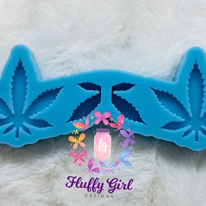 May include: Blue silicone mold with two cannabis leaf shapes. The mold is designed to create resin or polymer clay pieces.