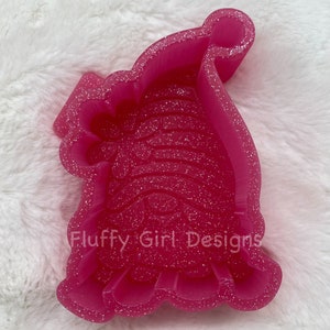 May include: Pink glitter resin mold shaped like a Santa hat. The mold has a detailed design and says "Fluffy Girl Designs" on the bottom.