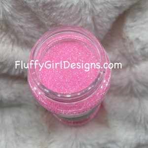 May include: A clear glass jar filled with pink glitter. The jar has a white label with the text "FluffyGirlDesigns.com" on it.