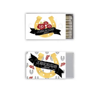 May include: A white matchbox with a gold horseshoe and red roses. The text "JOHNSON DERBY 2020" is printed on a black ribbon.
