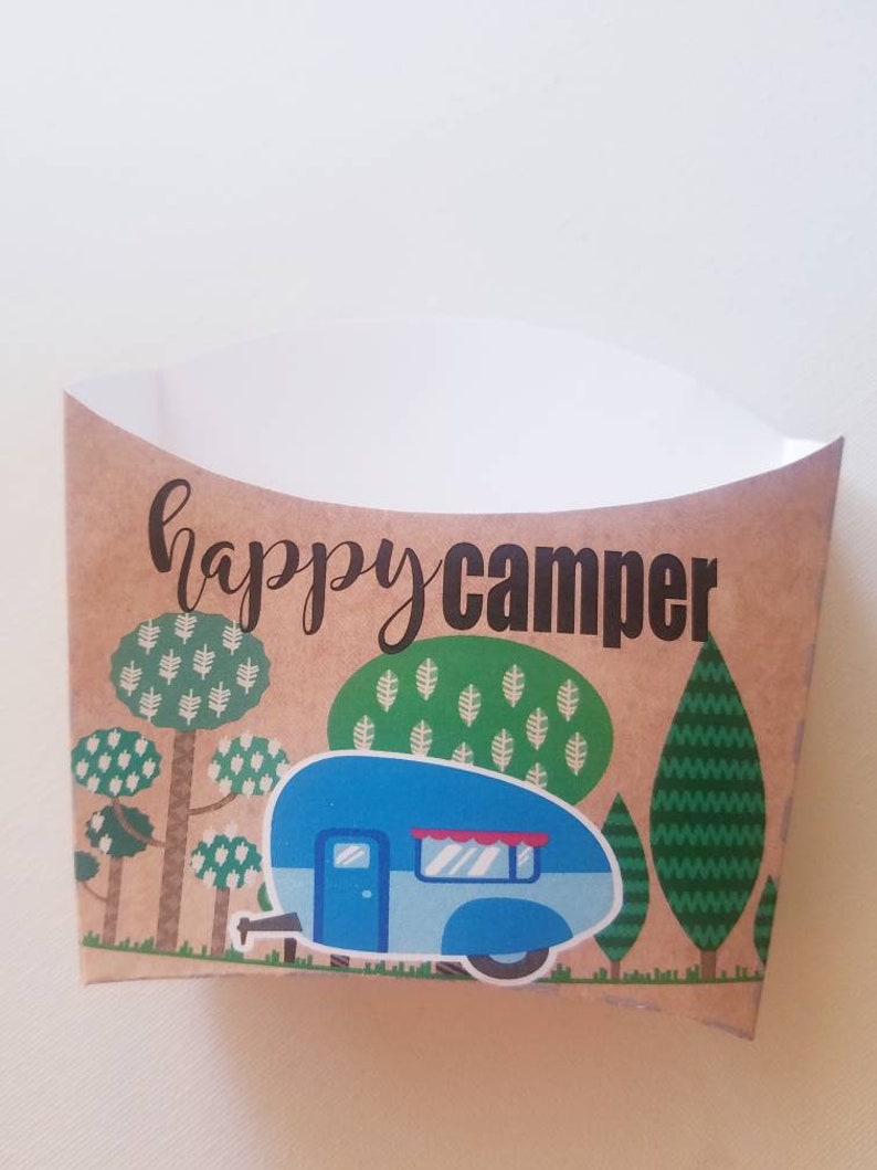 May include: A brown paper food container with a blue camper van illustration and the text "happy camper". The camper van is surrounded by green trees.