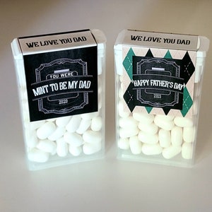 May include: Two clear plastic containers filled with white mints. The containers have black and white labels with the text "We love you Dad" and "Mint to be my Dad" and "Happy Father's Day".