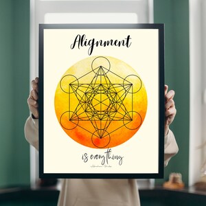 Puede incluir: Impresión artística enmarcada en negro con el texto "Alignment is everything" y un diseño geométrico. El diseño es un dibujo lineal negro sobre un fondo de acuarela amarillo y naranja. La cita se atribuye a Abraham Hicks.
