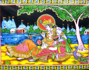 May include: A colorful tapestry depicting a Hindu deity couple, Krishna and Radha, in a romantic embrace. The scene is set in a lush garden with a peacock and a river in the background. The tapestry is framed with a decorative border.