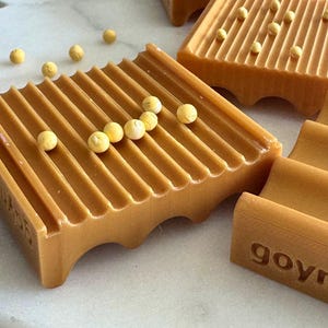 May include: Close-up of several brown soap dishes with a grooved design. Small yellow spheres are scattered on and around the soap dishes. The word "govr" is visible on the side of one dish.
