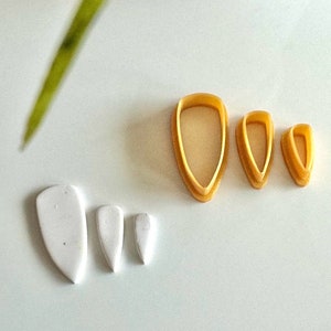 Peut inclure: Un ensemble de six emporte-pièces de différentes tailles. Trois sont blancs et trois sont jaunes. Les emporte-pièces jaunes sont en forme de larme avec une pointe arrondie. Les emporte-pièces blancs sont en forme de larme avec une pointe pointue.