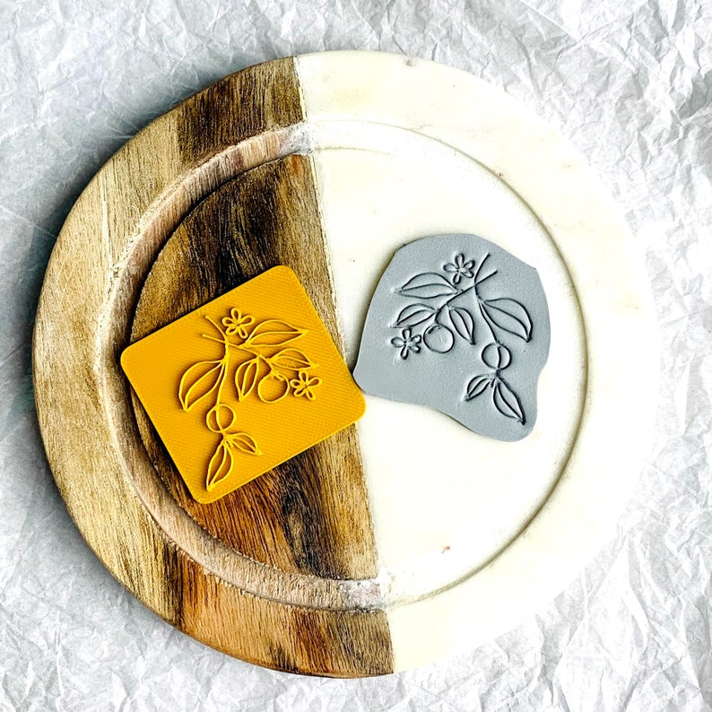 May include: Two rubber stamps with a floral design. One stamp is yellow and the other is gray.