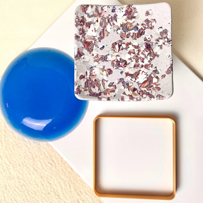 May include: Three decorative trays, one blue, one white with a gold frame, and one white with a speckled pattern in shades of brown, pink, and white.
