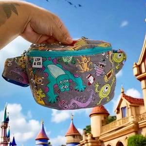 May include: A grey fanny pack with a blue zipper and a colourful print of characters from the movie Monsters Inc. The fanny pack has a small tag that says "LTP & CO."